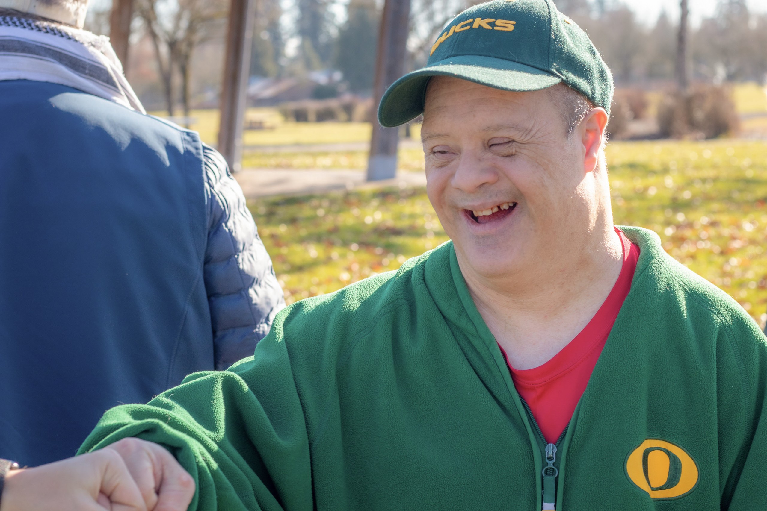 Man with down syndrome enjoying a day outside in the park and laughing