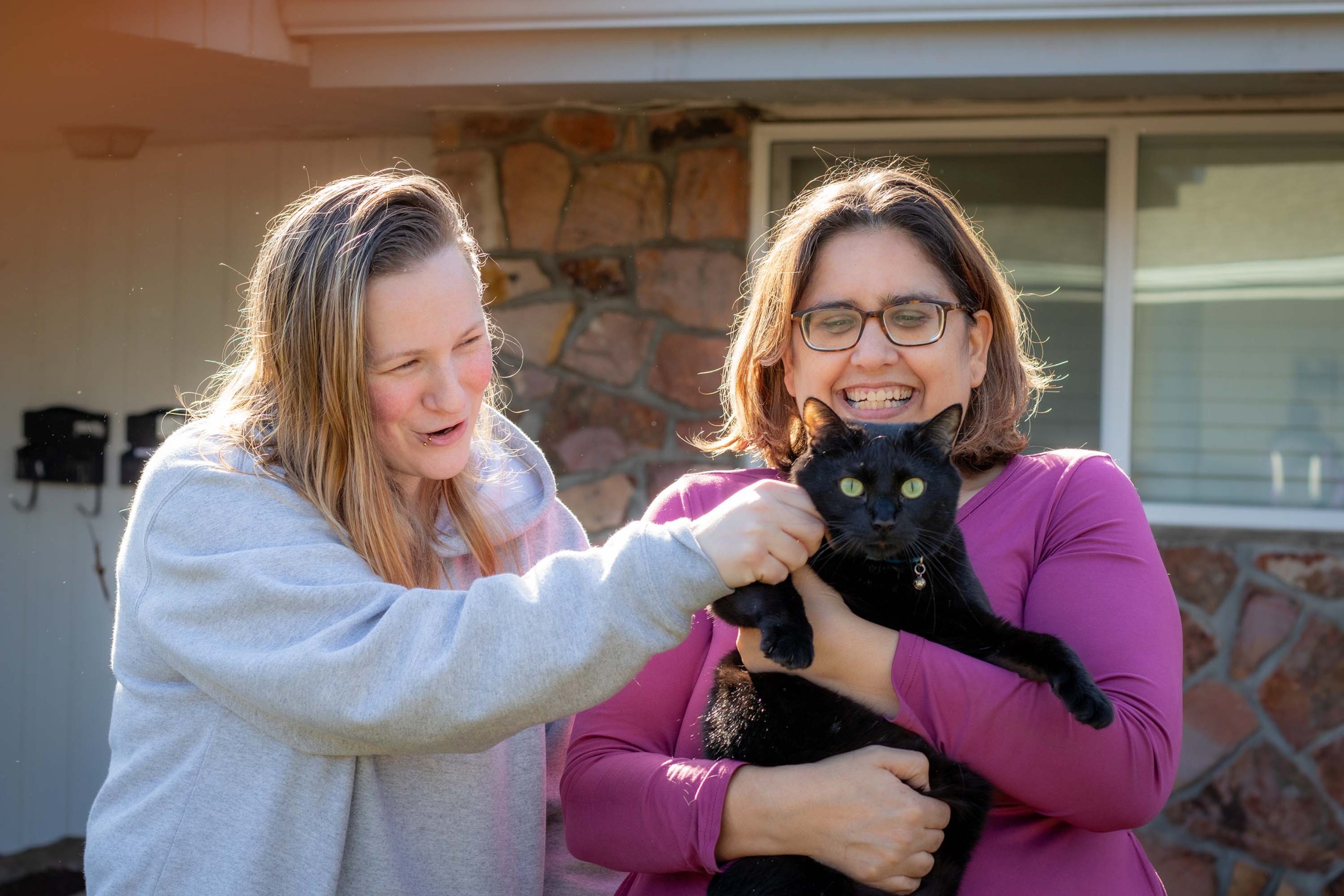 Two women holding a cat and smiling