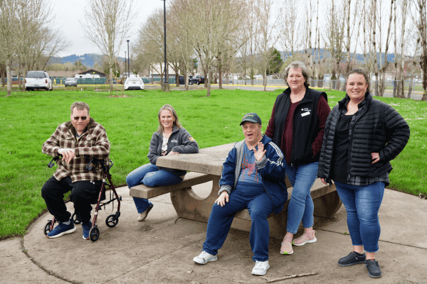 MV Advancements volunteers and program participants gathered at a park picnic table during a weekly Easy Walks community activity